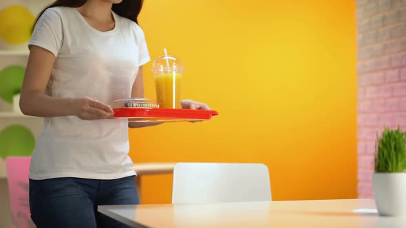 Happy Woman Putting Tray With Salad and Fresh Orange Juice on Table, Snack Bar