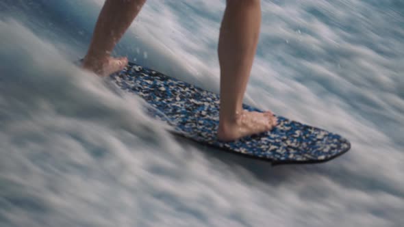 Surfer Girl Rides a Surfboard on an Artificial Wave in Wave Pool Machine