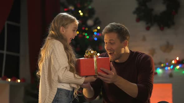 Cute Little Daughter Giving Christmas Present for Happy Daddy, Lights Sparkling