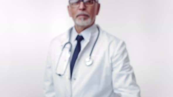 Grayhaired Doctor with Beard Shows Pill to Camera