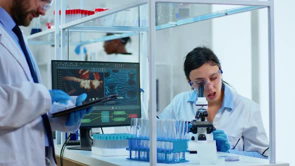 Team Medical Scientist Conducting DNA Experiments Under Digital Microscope