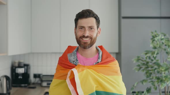 Portrait Shot of Middle Aged Smiled Gay Man Wearing Rainbow Flag Over His Shoulder and Looking at