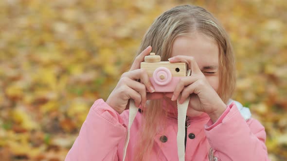 Teenage Girl with Toy Cameras Takes Pictures in the Autumn Park.