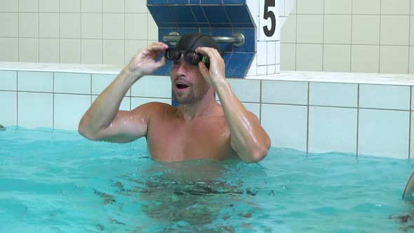 A Professional Swimmer Swims To an Edge of an Indoor Pool and Celebrates