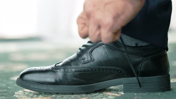 Closeup European Male Hands in Wrist Watch Tying Shoelace on Formal or Festive Classic Black Shoe