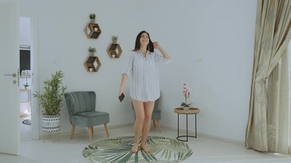 Slow motion of Happy brunette woman in a shirt and headphones dancing at home