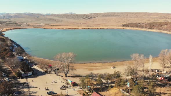 People Walking By The Round Blue Lake 