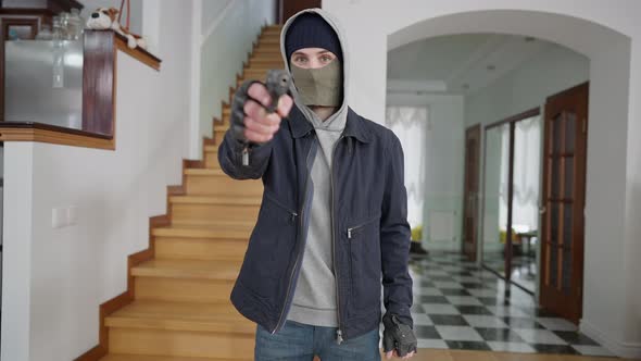 Middle Shot Portrait of Young Caucasian Masked Man Raising Hand with Gun Looking at Camera