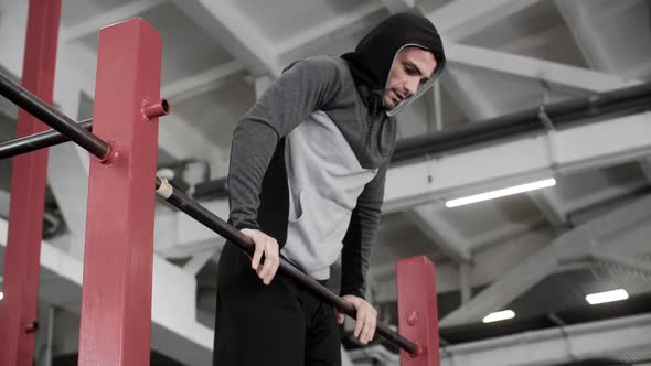 Athlete Man in Hoodie Pulling Up on Crossbar at Sport Training Gym