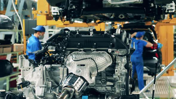 Factory Unit and Employees Working with Car's Engine