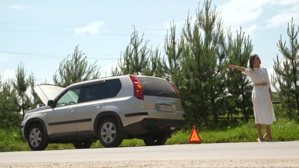 Business woman waits for assistance near her car broken down on the road side