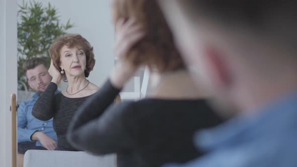 Pretty Senior Mature Woman Looking in the Mirror at Her Reflection, Touching Her Hair