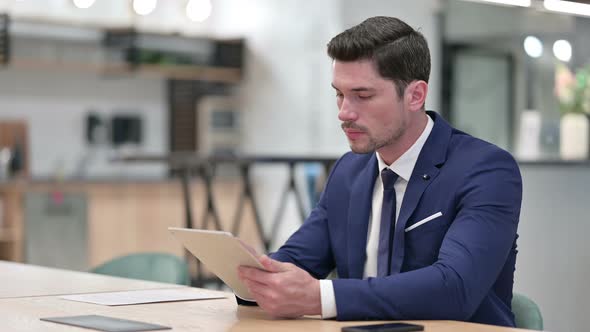 Serious Professional Businessman Using Tablet in Office 