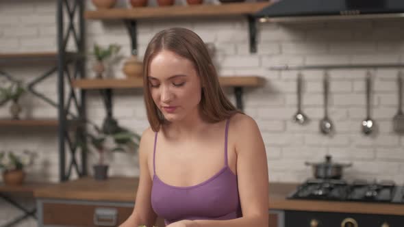 Woman siting at a table on the home kitchen. Sporty girl eating cabbage leaves adheres to a diet