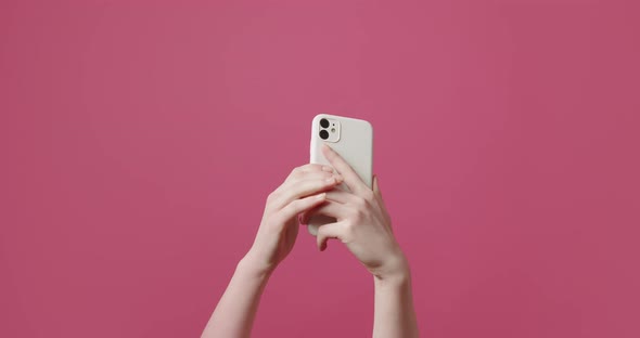 The Young Woman Uses a SmartPhone and Shows the Like Symbol on Pink Background