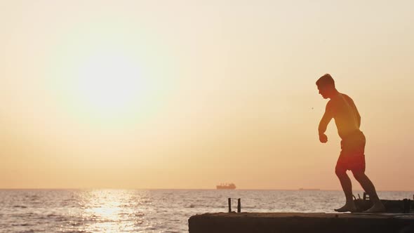 Young Man Jumping From Sea Pier and Doing Backflip During Beautiful Sunrise Super Slow Motion