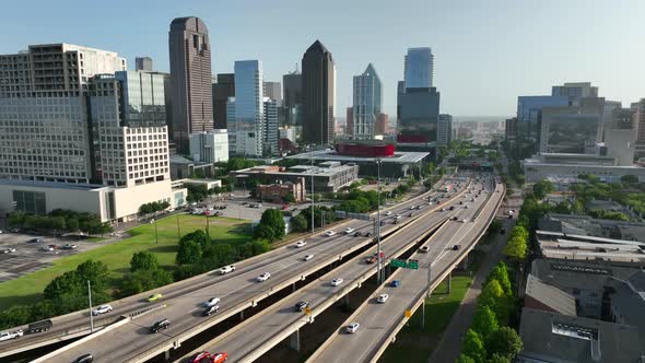 Urban American city in Texas. Traffic on freeway driving during golden hour light. Aerial pullback r