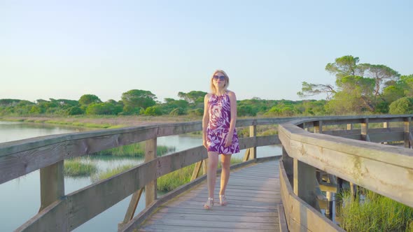 Blonde Girl Walks on a Wooden Walkway