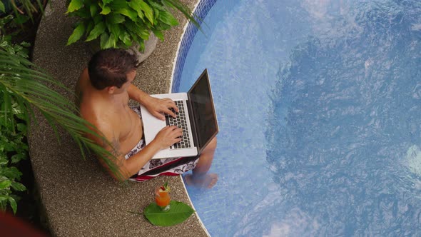 Man sitting on edge of hot tub using laptop computer. Shot on RED EPIC for high quality 4K, UHD, Ult