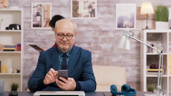 Elderly Man with Glasses Browsing on Mobile Phone