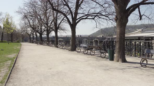 A Deserted Walkway with Benches Through a Park Without People During the Coronavirus Pandemic