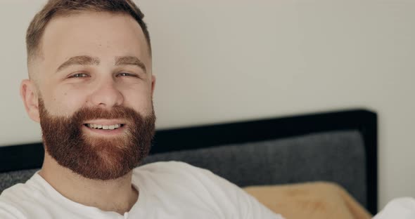 Portrait of Smiling Adult Man in Casual Clothes Lying on Bed in Morning. Close Up View of Happy Good