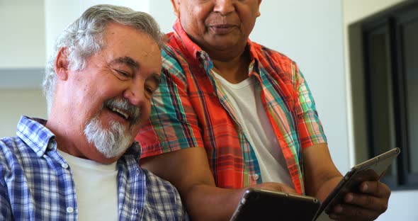 Happy senior friends using digital tablet on sofa