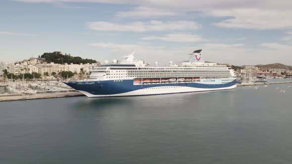 Massive luxury cruise ship docked at Cartagena port, Spain; drone pan