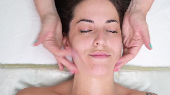 Cosmetologist Making Facial Massage with Moisturizing Cream on Woman Face