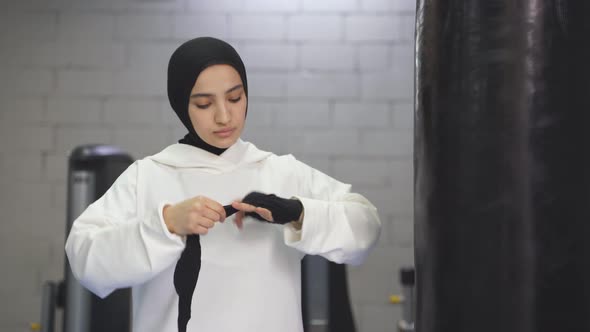 Strong Muslim Woman Prepares for Training Boxing Alone in the Gym Woman Ties Ricky Elastic Bandages