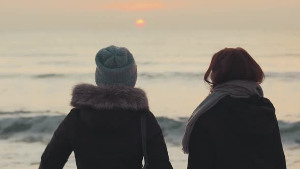 Two Beautiful Girls Have a Good Time at Sea at Sunrise or Sunset