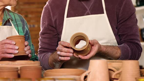 Male and female potter interacting while examining a pot