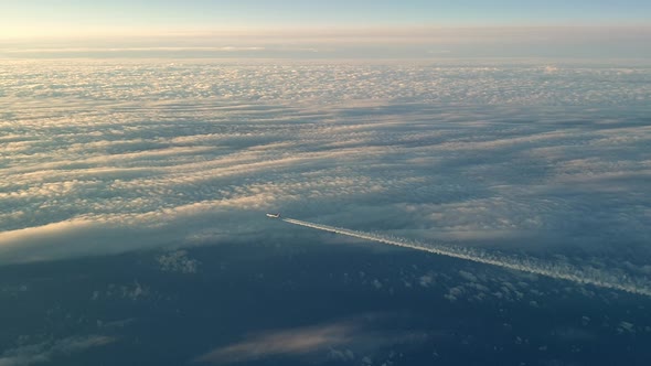 Incredible view from the cockpit of an airplane flying high above the clouds leaving a long white co