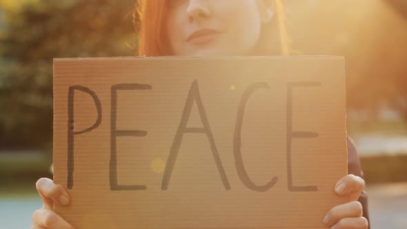 Close Up Female Hands Hold Cardboard with Written Word Peace Symbolic Banner Attractive Young Woman