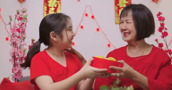 Happy Asian Girl Giving Her Grandmother Orange for Chinese New Year Blessing Gift.