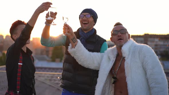 Group of Cheerful Caucasian Friends Toasting Drinking Champagne on Roof in Urban City at Sunset