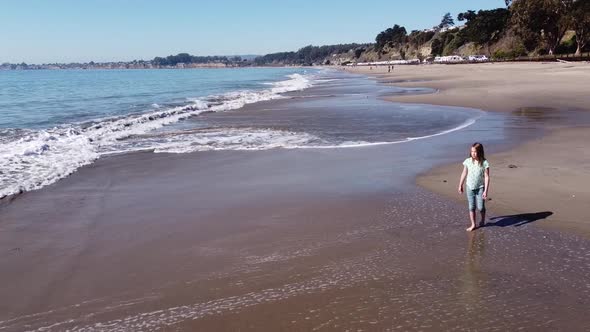 Girl with long brown hair enjoys warm water of California coast in Seacliff State Beach