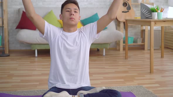 Young Asian Man Doing Yoga Sitting on the Mat Close Up