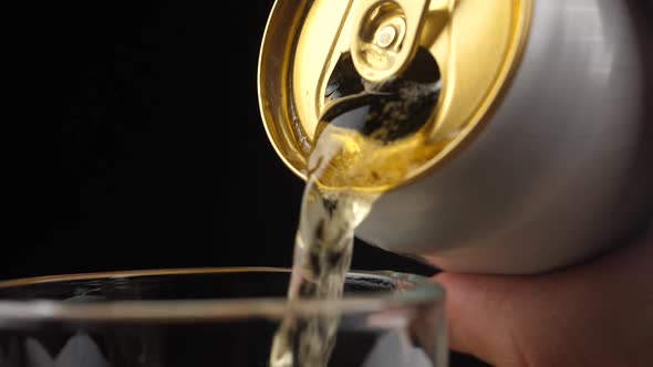 Pouring Cold Beer into a glass with water drops. Can of Beer close up.