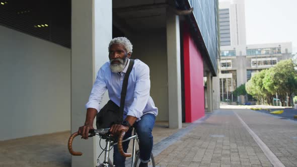 African american senior man riding a bicycle in corporate park