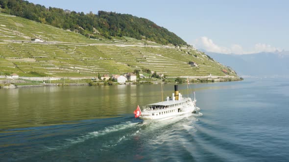 Aerial shot passing behind CGN steam Belle-Epoque ship on Lake Léman in front of Lavaux. The Alps in