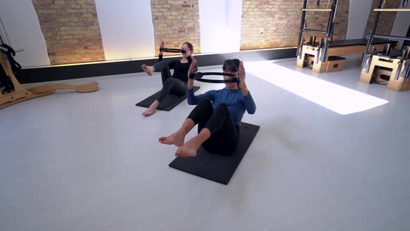 Women doing exercises with pilates ring in studio
