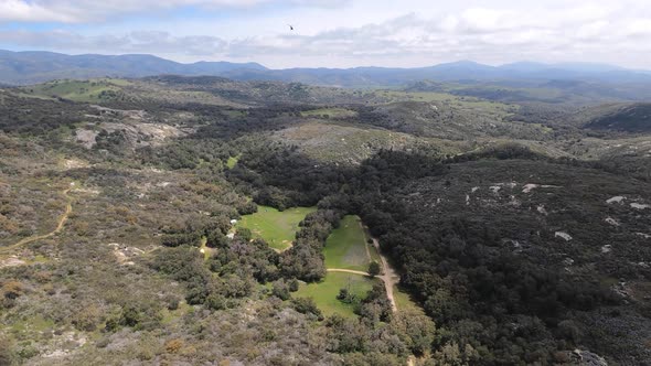 Aerial wide view chasing a black helicopter over the hills near Santa Ysabel, California. Rugged tra