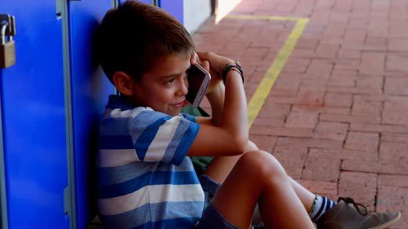 Schoolboy talking on mobile phone in locker room 4k