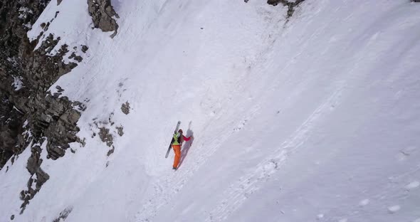 Aerial drone view of a mountain climber climbing up with crampons in the snow.