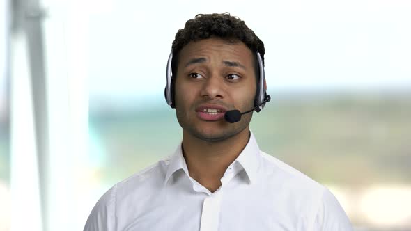 Dark-skinned Man with Headset on Blurred Background.