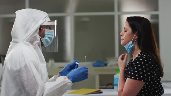 Medical worker in protective clothing taking swab test from female patient