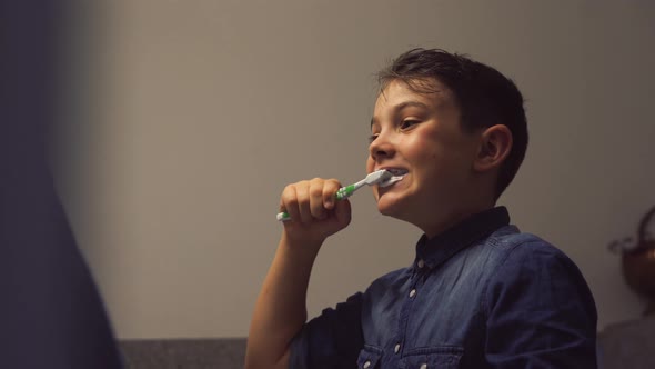 Cute boy brushing teeth in cozy bathroom