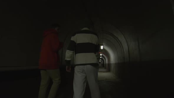 Two Friends Walking in Dark Tunnel and Chatting