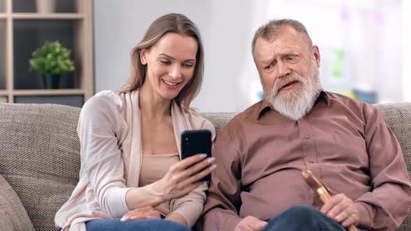 Happy Young Adult Daughter Granddaughter and 80s Father Grandfather Studying Use Smartphone